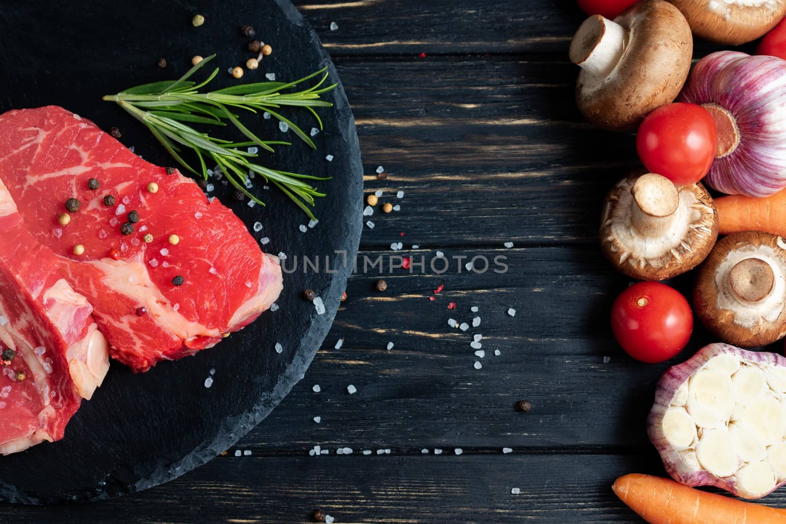 On one side of the table are vegetables on the other side of a beautiful juicy, raw beef meat. Choose your food. by andreonegin