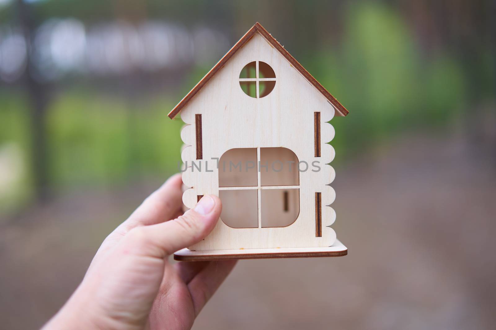 Miniature wooden house in male hand outdoor nature. Real estate concept. Modern housing. Eco-friendly energy efficient house. Buying home outside the city Fresh air. Mortgage, loan.