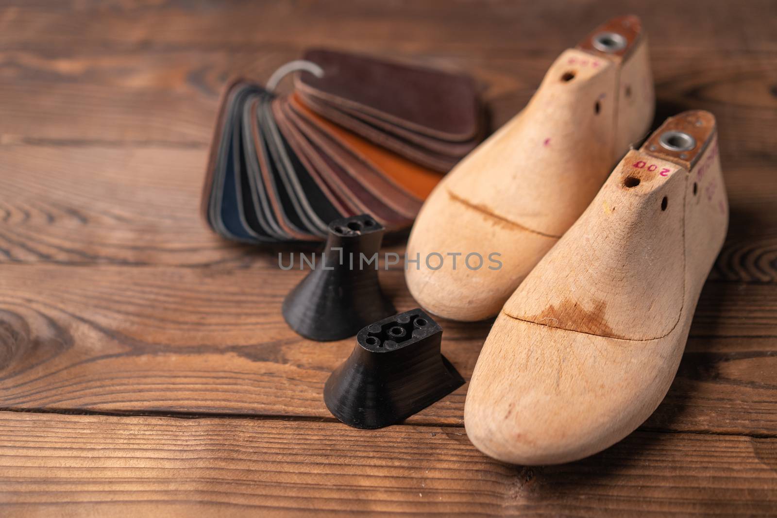 Leather samples for shoes and wooden shoe last on dark wooden table. by andreonegin