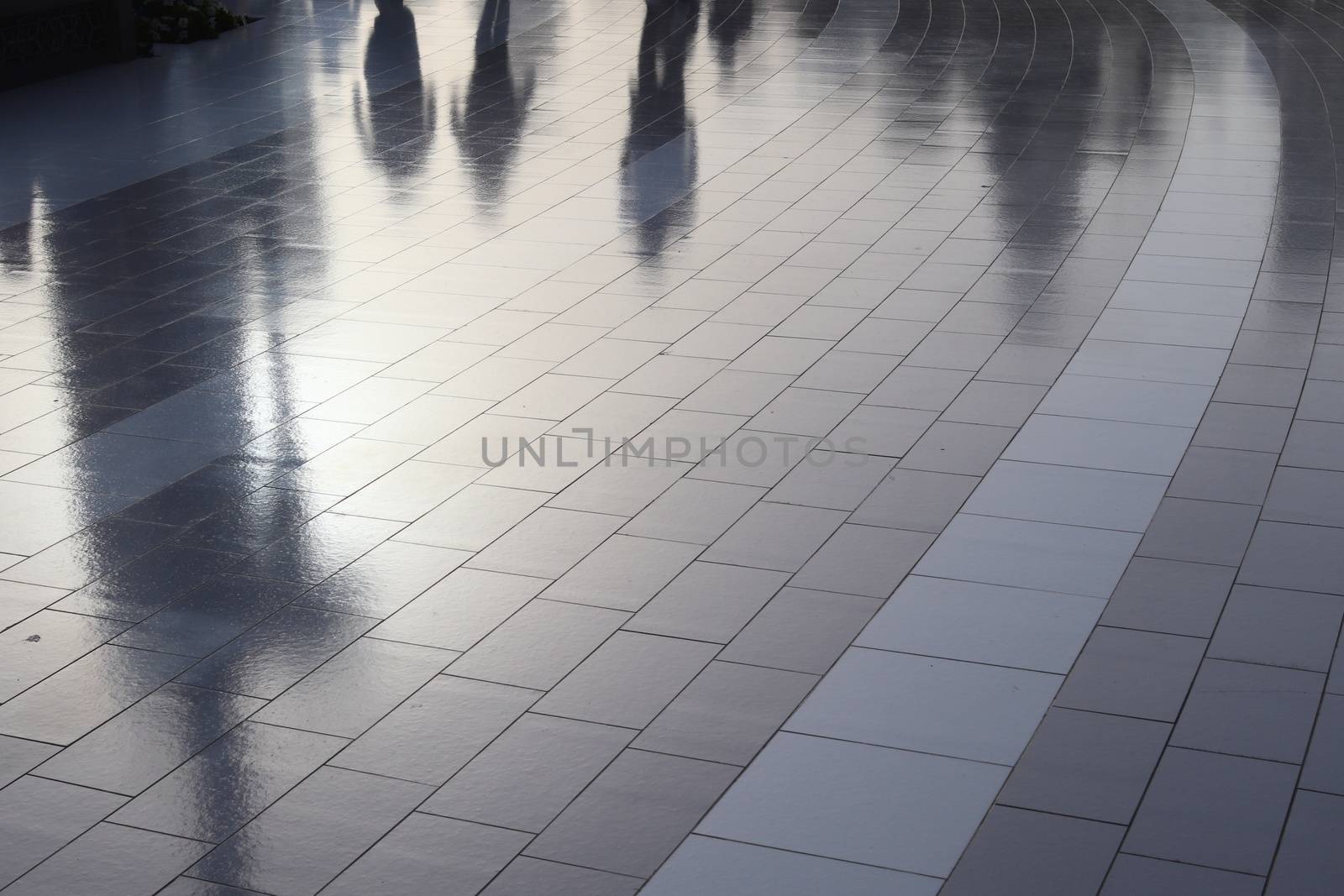 Diffuse reflections of pedestrians walking a marble sidewalk