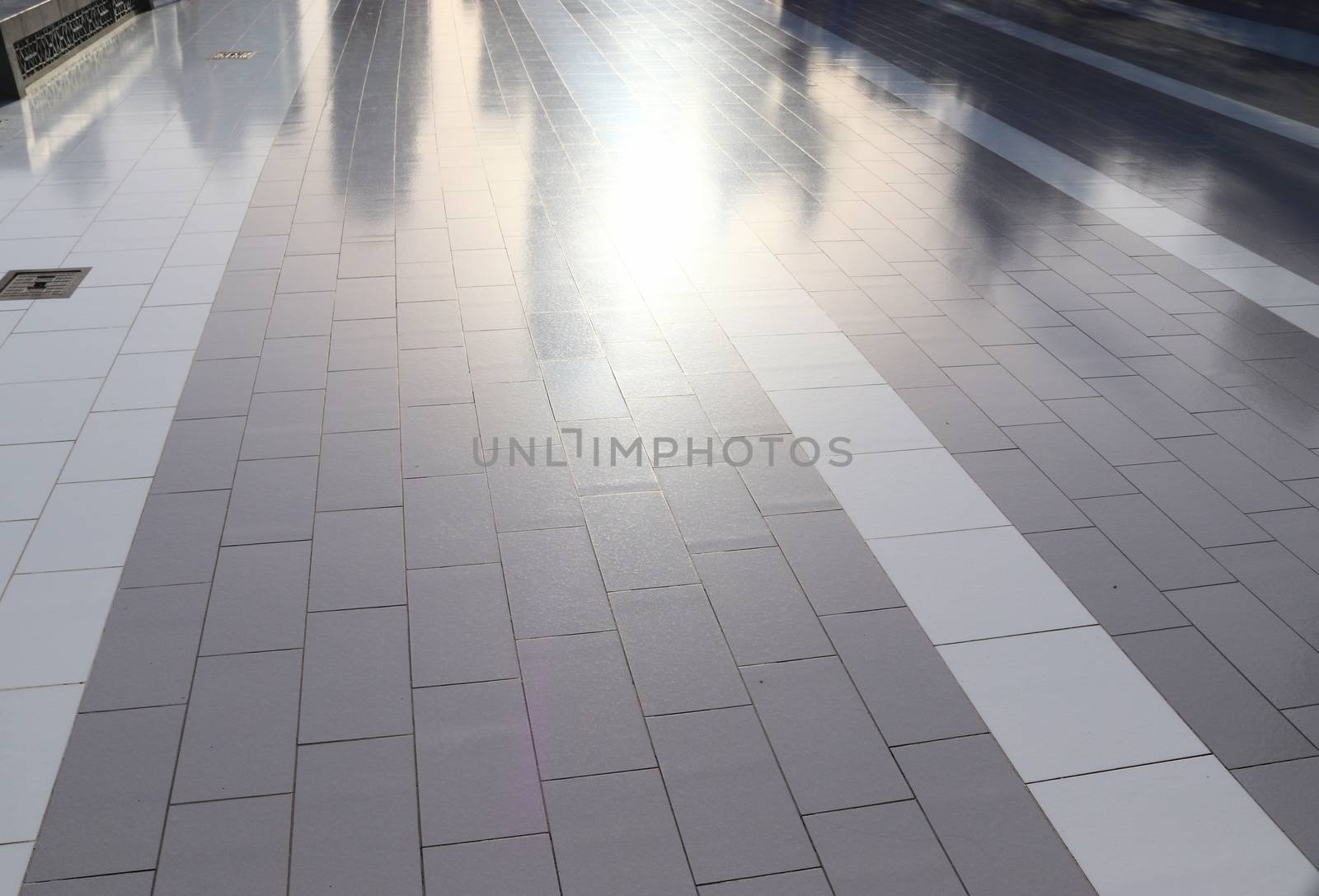 Diffuse reflections of pedestrians walking a marble sidewalk