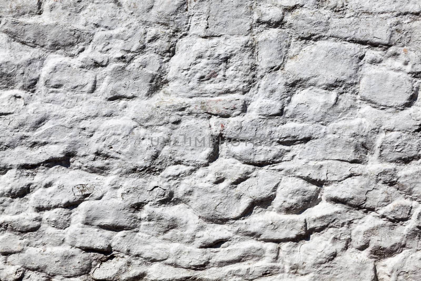 Old grey white weathered rough stone wall texture  by ant