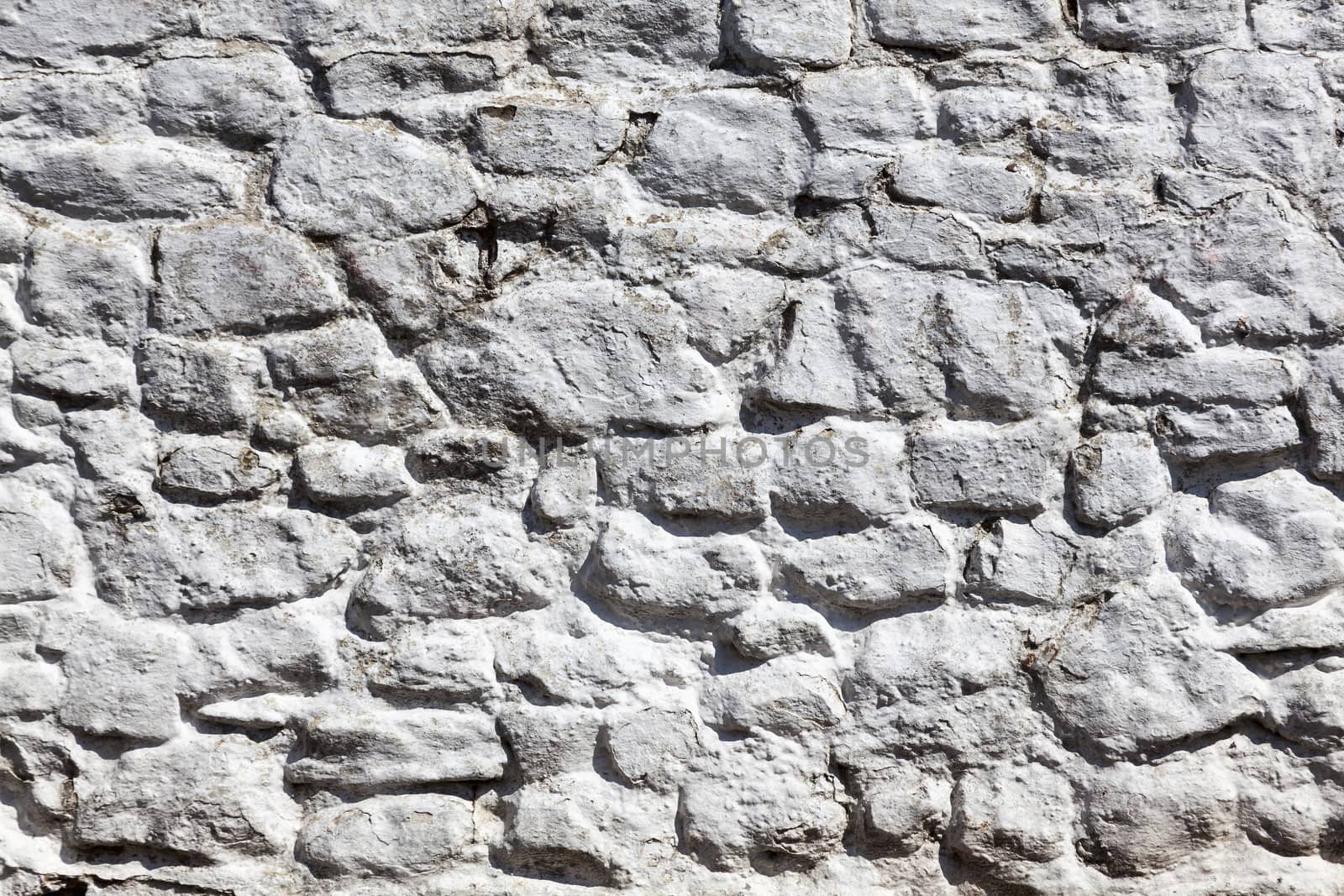 Old grey white weathered rough stone wall texture background