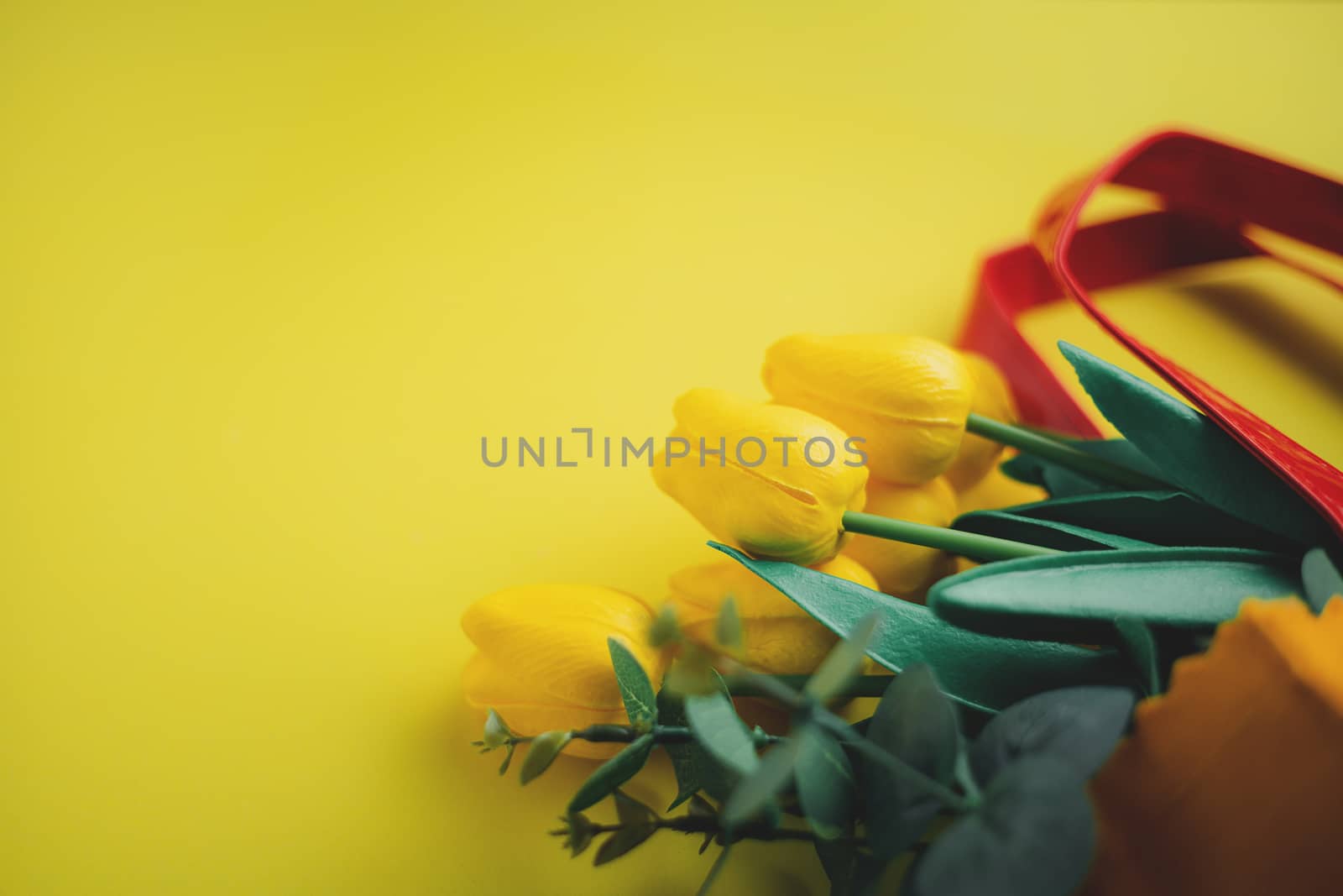 Selective focus of yellow tulips in shopping bag on yellow background for nature decoration and springtime concept