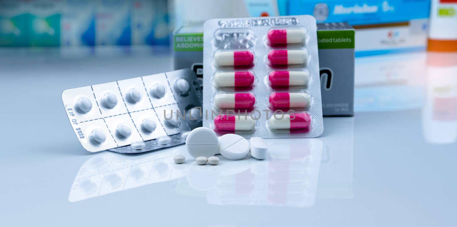 Pills in pharmacy shop. White tablets pills on blurred capsule in blister pack and white tablets pills in pack near drug box package. Pharmacy products. Pharmaceutical industry. Drugstore business.