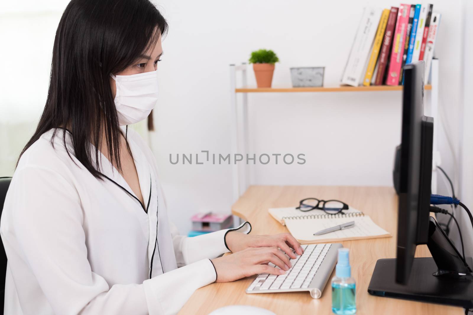 A beautiful Asian businesswoman wearing a mask and cleaner gel to protect COVID-19 before start working from home with safety and happiness.