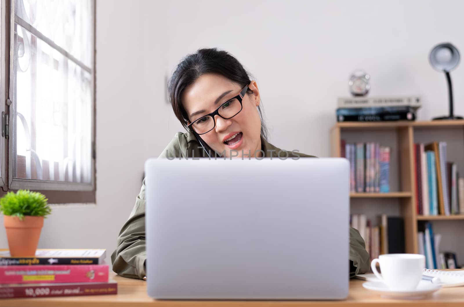 Modern young Asian woman working from home and talking with a pa by animagesdesign