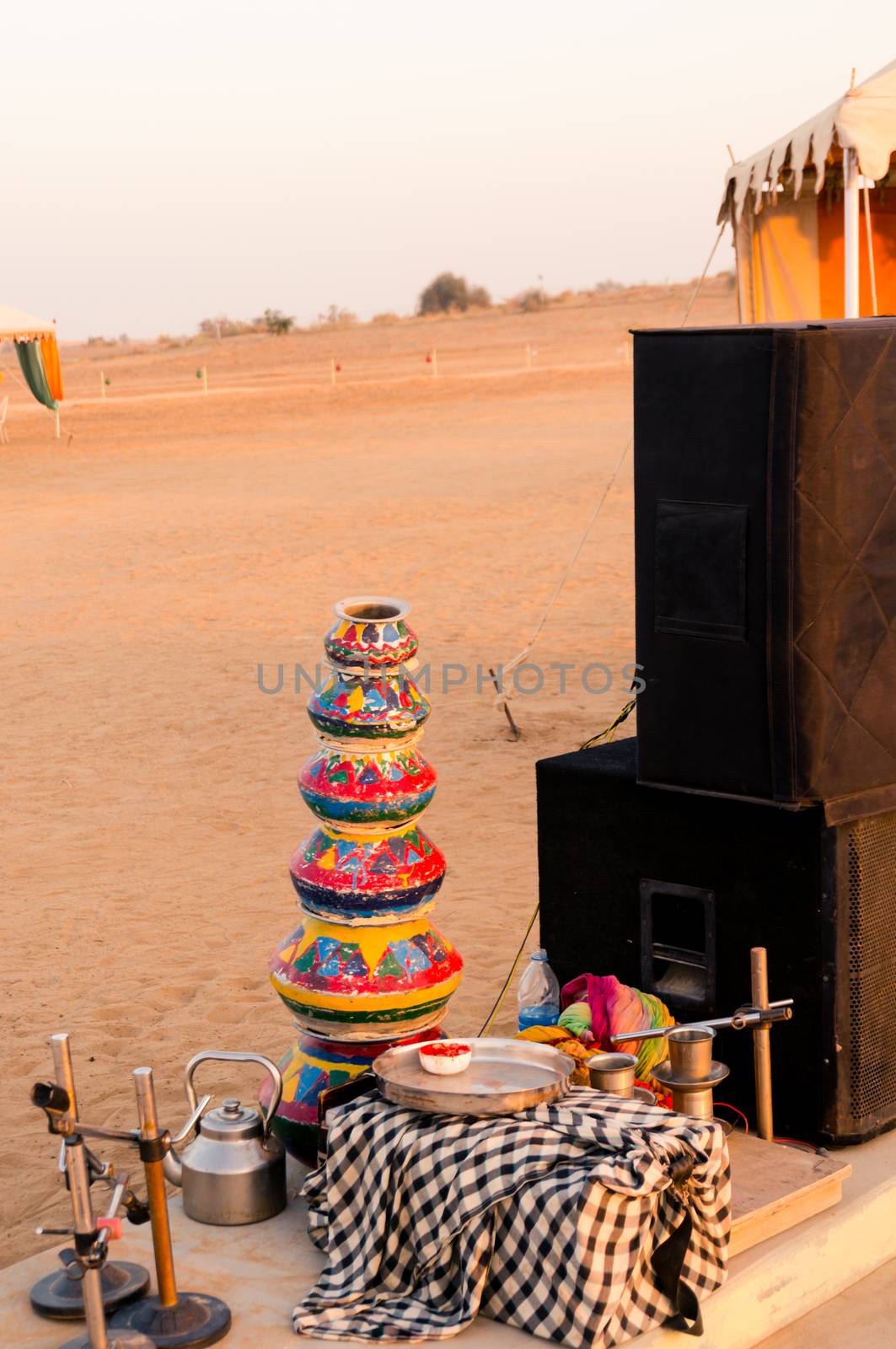Evening shot showing the props like clayware pots, clay pots, dishes, kettle, mics and more as props for traditional rajasthani dances for visitor entertainment at a desert camp by Shalinimathur