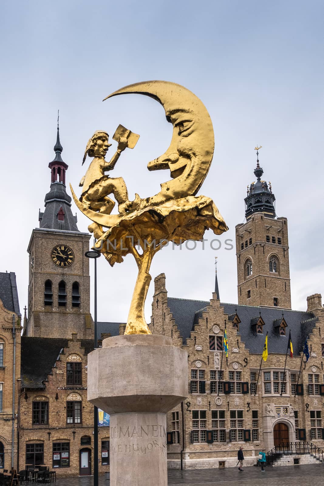 Diksmuide, Flanders, Belgium -  June 19, 2019: Grote Markt. Golden Manneke UIt de Mane statue between brown brick towers of Saint Nicolas church and City Hall. light blue sky.