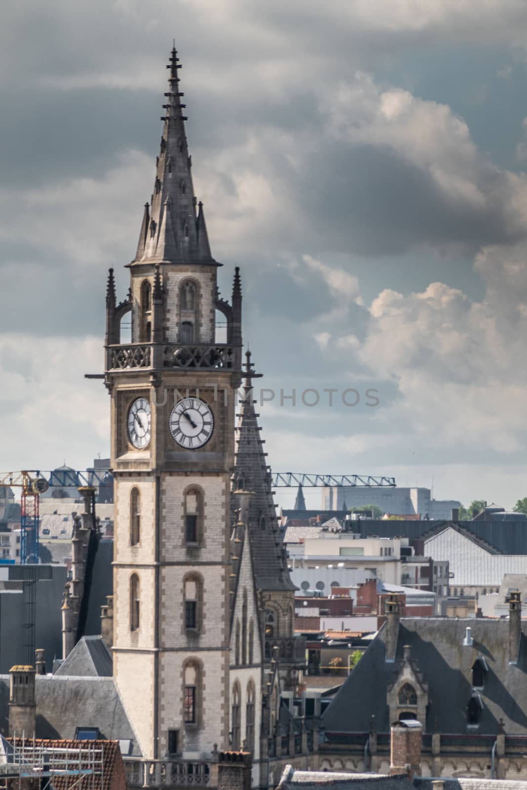 Gent, Flanders, Belgium -  June 21, 2019: Shot from castle tower, view over city roofs shows closeup of Postal Service tower under heavy white cloudscape with blue patches.