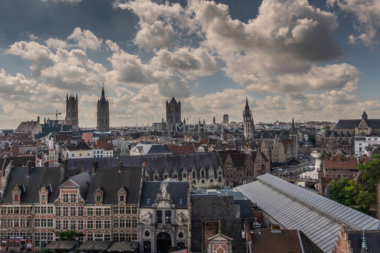 Gent, Flanders, Belgium -  June 21, 2019: Shot from castle tower, view over city roofs shows six most important and historic towers of Belfry, churches, Postal service, and university. Fish market gate. Cloudscape with blue patches.