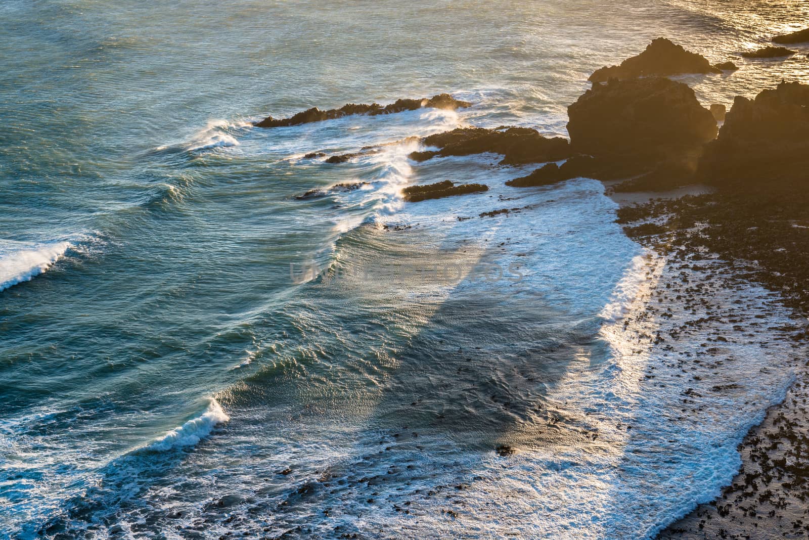 Sunset view of the Pacific Ocean coast, waves and cliffs at Nugget Point, New Zealand