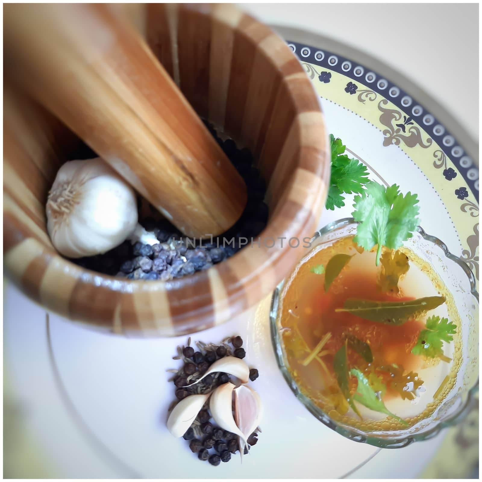 indian traditional food tomato pepper soup in bowl with its spices pepper cumin garlic beautifully kept in white plate