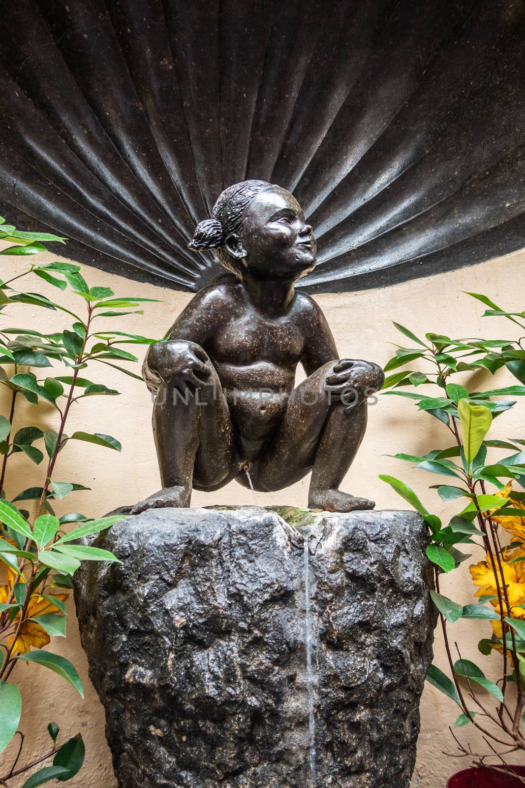 Brussels, Belgium - June 22, 2019: Closeup of iconic and original Jeanneke Pis statue, urinating on black rock.