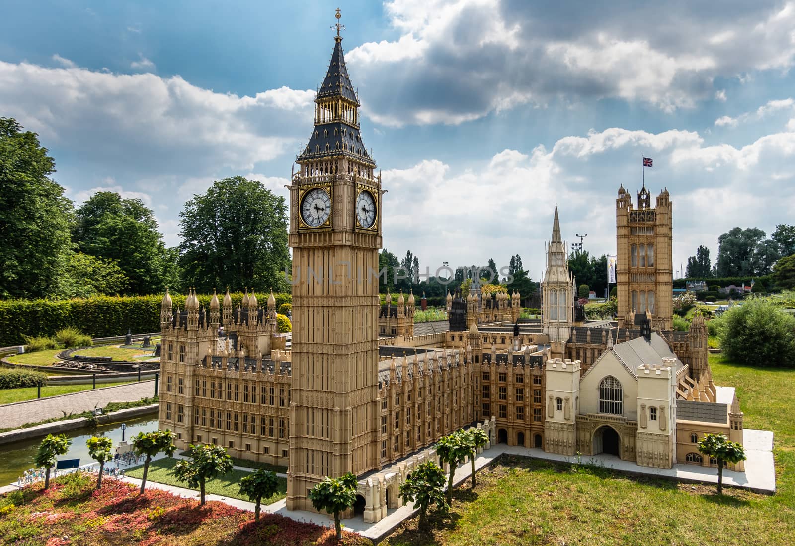 Brussels, Belgium - June 22, 2019: Mini-Europe exhibition park. London Big Ben clock tower and Parliament House built in miniature in park under blue sky with cloudscape and green foliage.