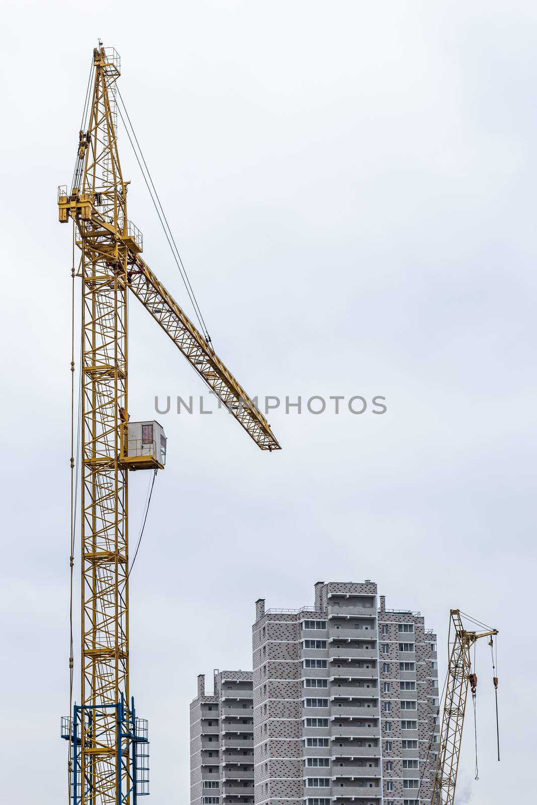 Boom crane on a background of cloudy cloudy sky and building.