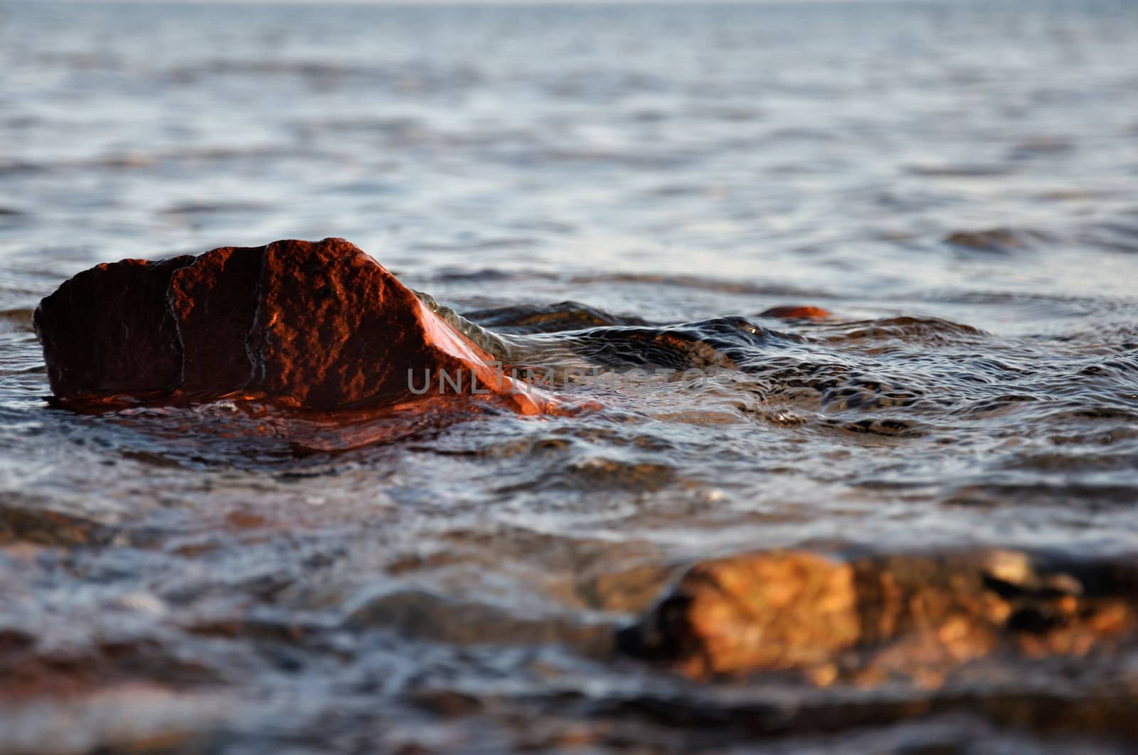 Small stones and rocks at the edge of the sea and in the waves