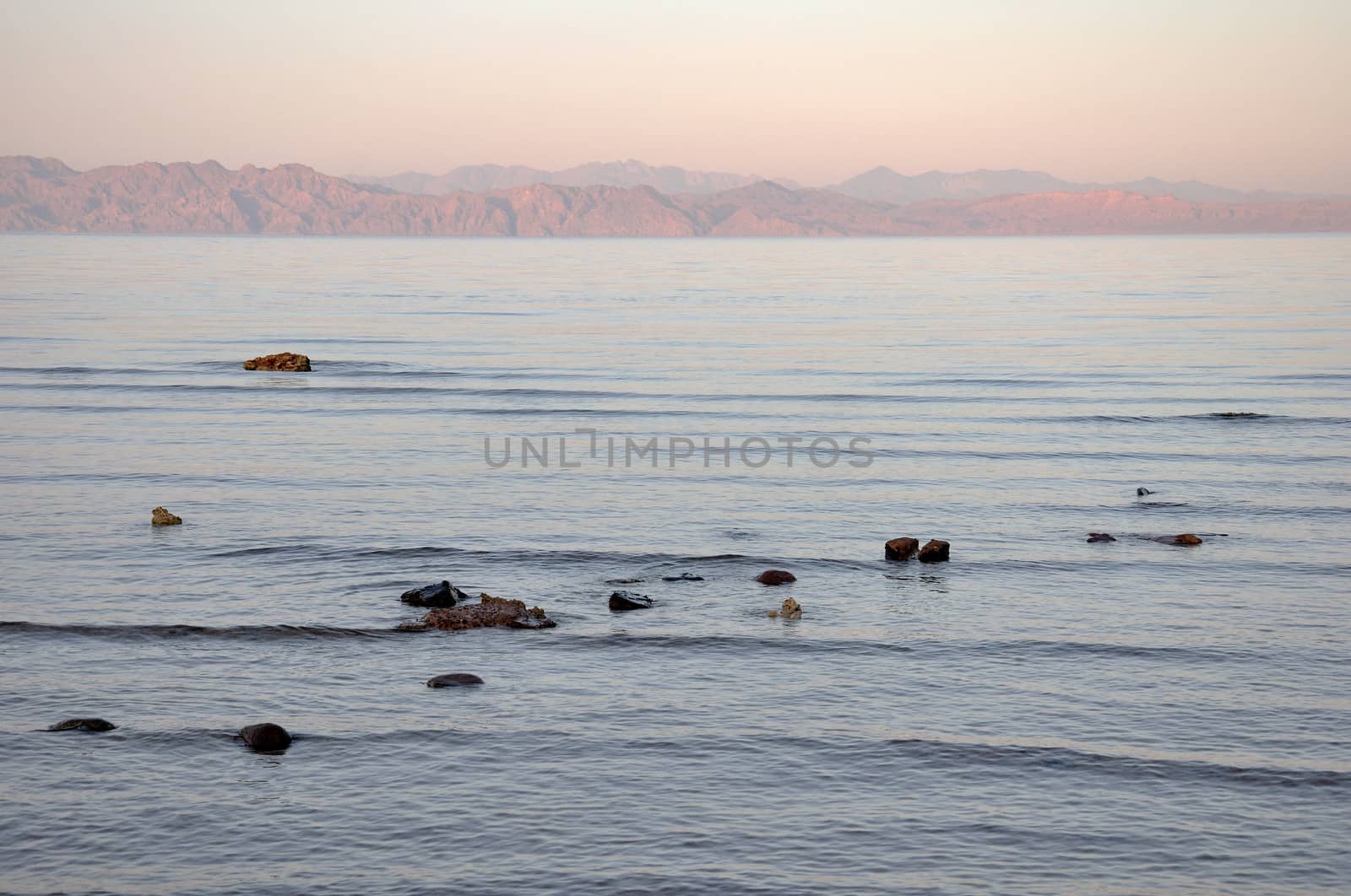 Small stones and rocks at the edge of the sea and in the waves