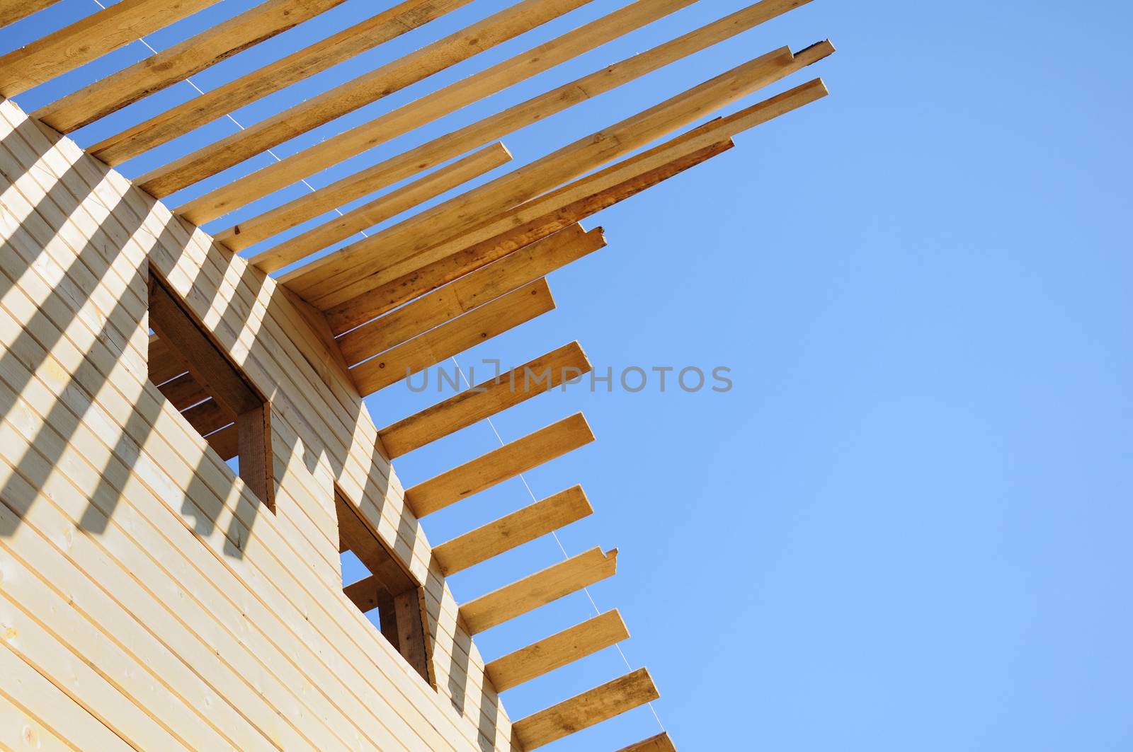 The unfinished wooden roof and empty windows at the blue sky background, left side view