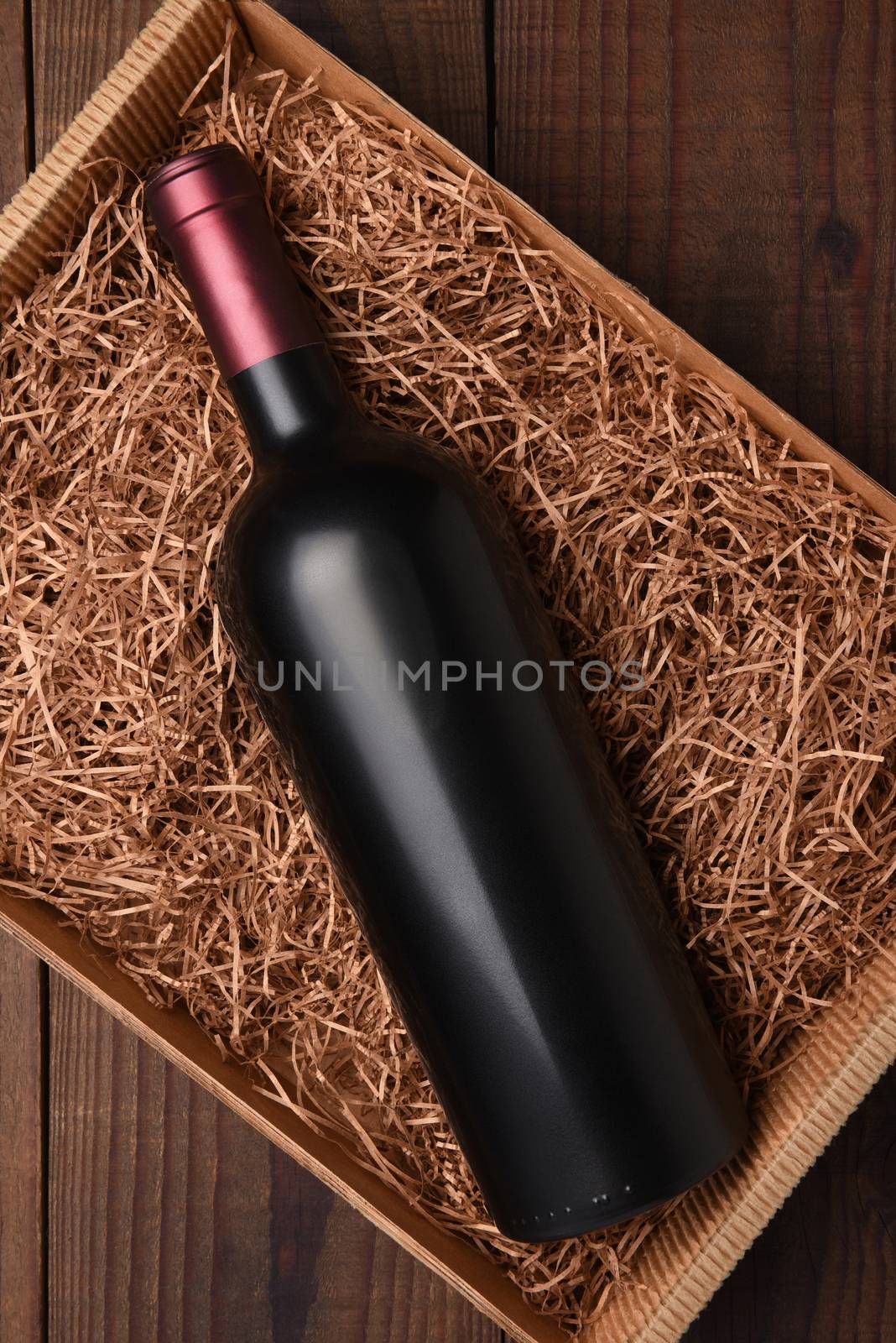 Cabernet Wine Bottle in Packing Straw: High angle shot of a single bottle with no label in a cardboard box with straw packing.