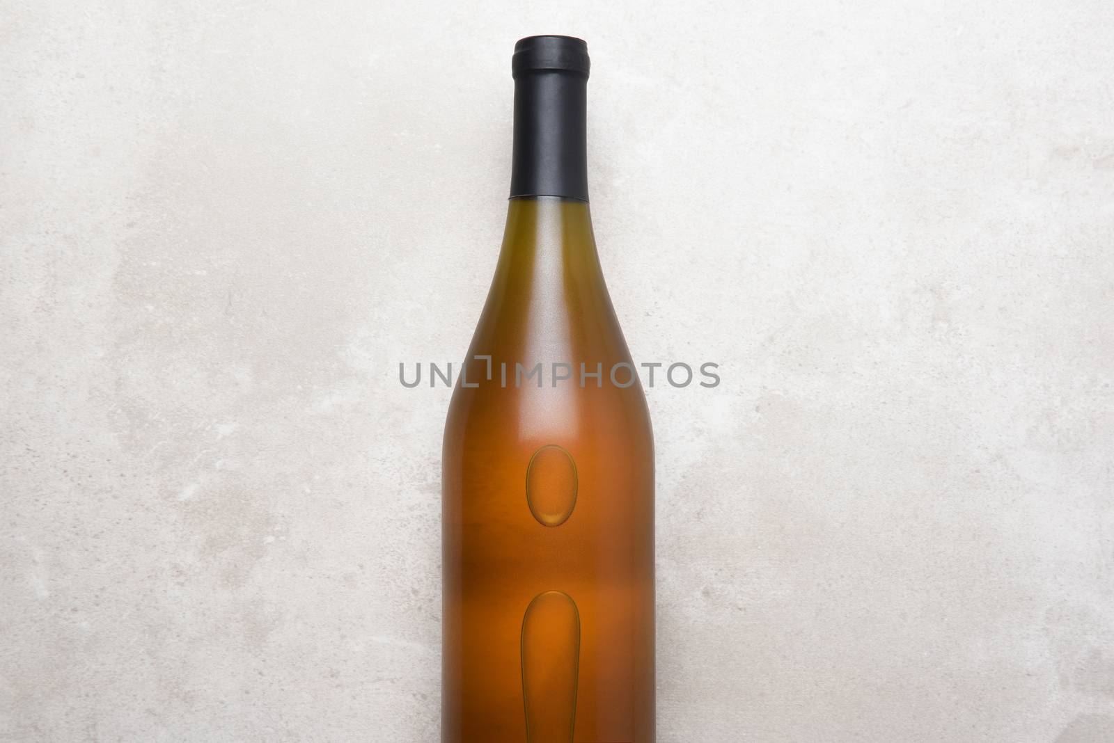 Chardonnay Wine: Top view of a single bottle on a concrete counter top. Bottle is in the middle with copy space on both sides.