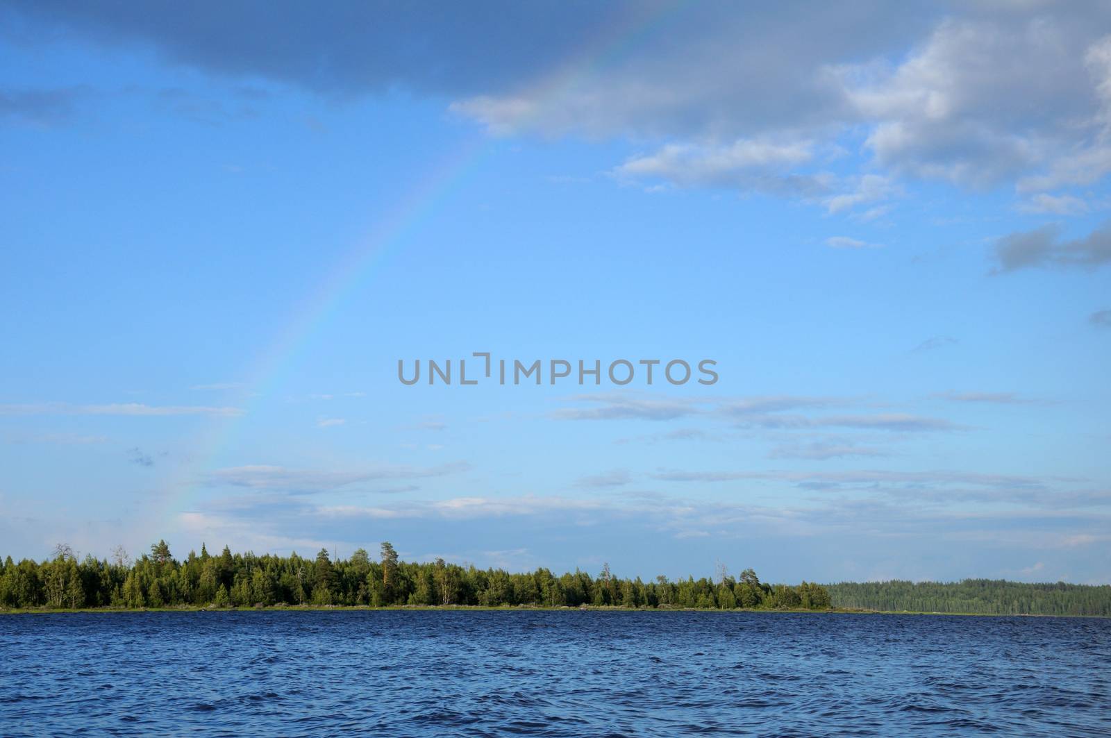 Video shows saturated and colorfull rainbow under single cloud in the sky over lake's surface