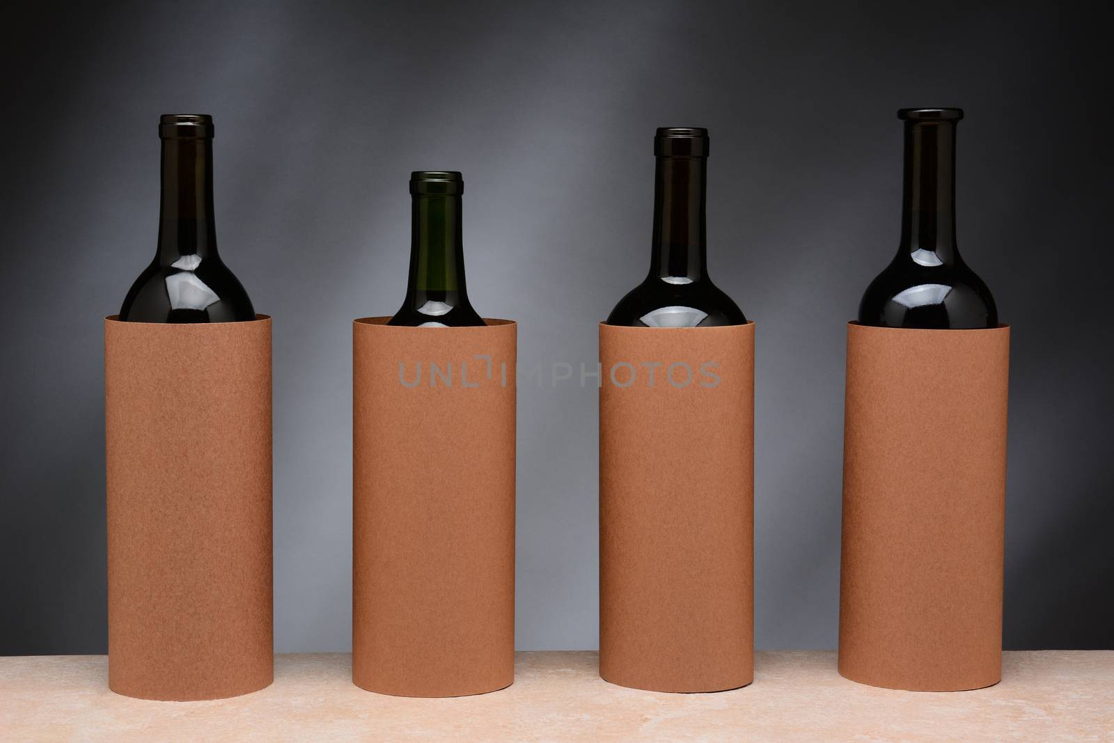 Four different wine bottles set up for a blind wine tasting. The bottles are covered by blank cylinders to hide the label. Horizontal format. 