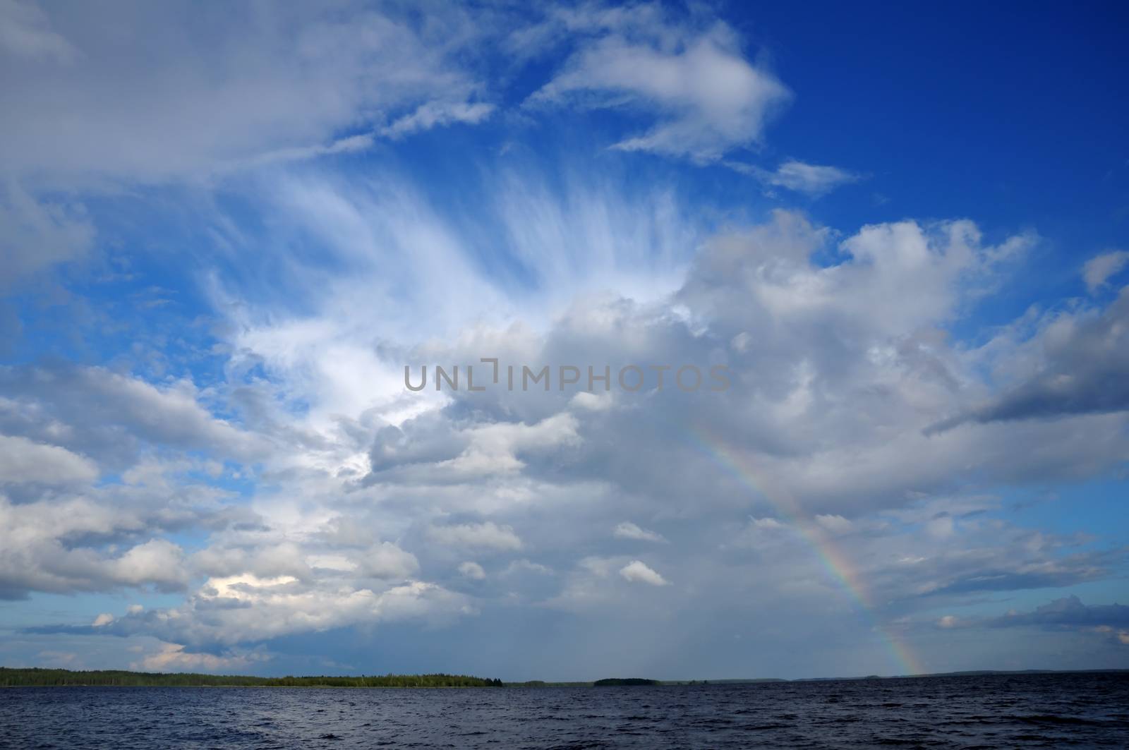 Video shows saturated and colorfull rainbow under beautiful cloud in the sky over lake's surface