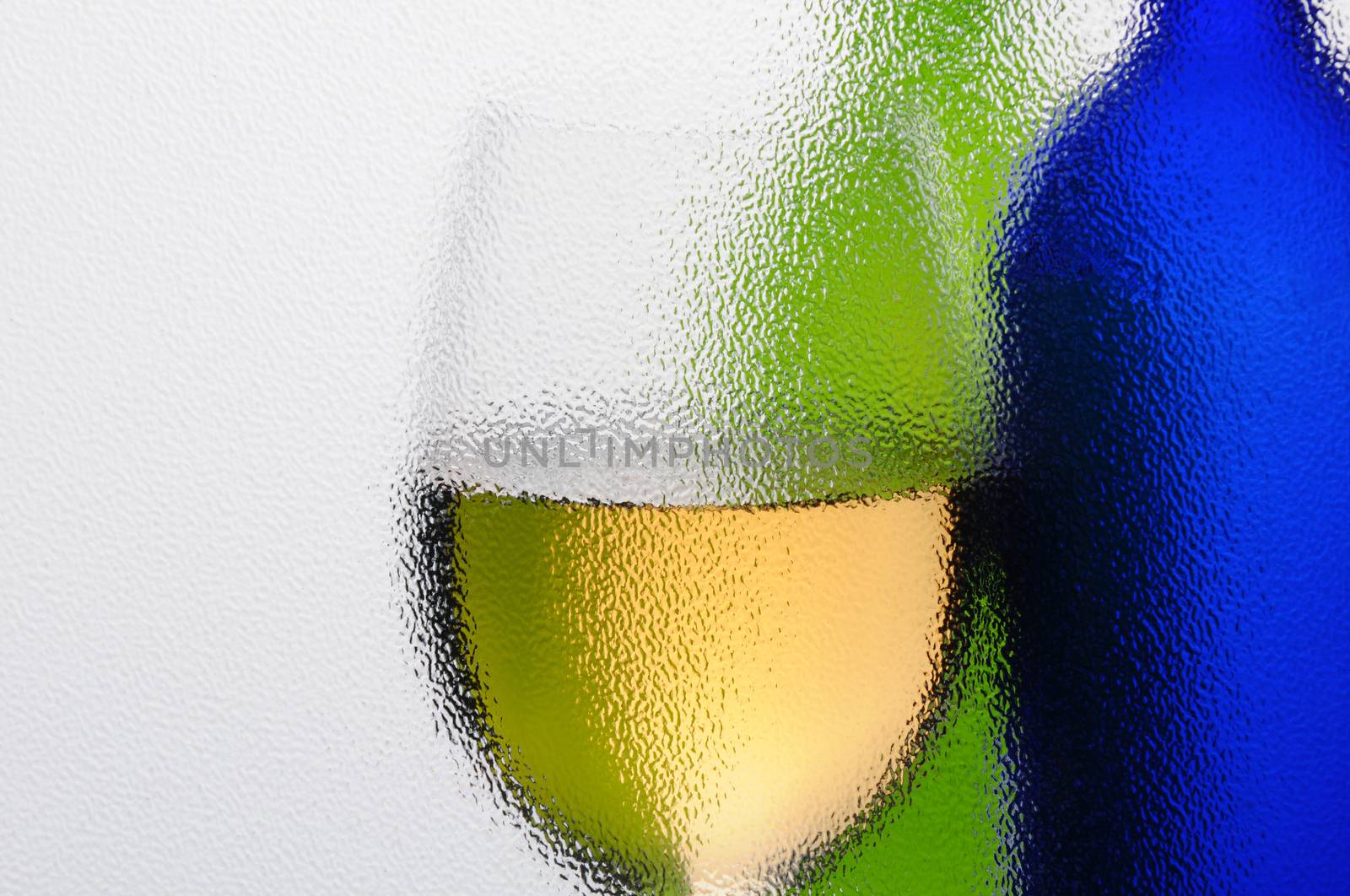 Wine Bottles and Wineglass seen through a textured window with backlight. Horizontal composition with copyspace.