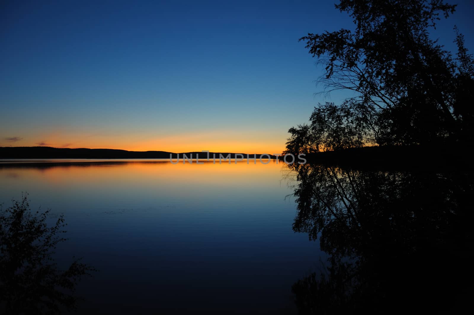 The final stage of a sunset above the huge lake in Karelia region. The picture is colorful and relaxing.