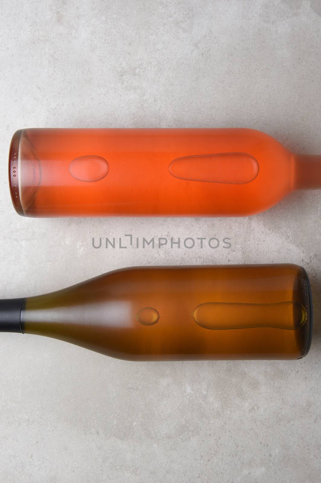 Chardonnay and Blush Wine Bottles: Two bottles on a concrete table top with copy space at the top and bottom of the frame.