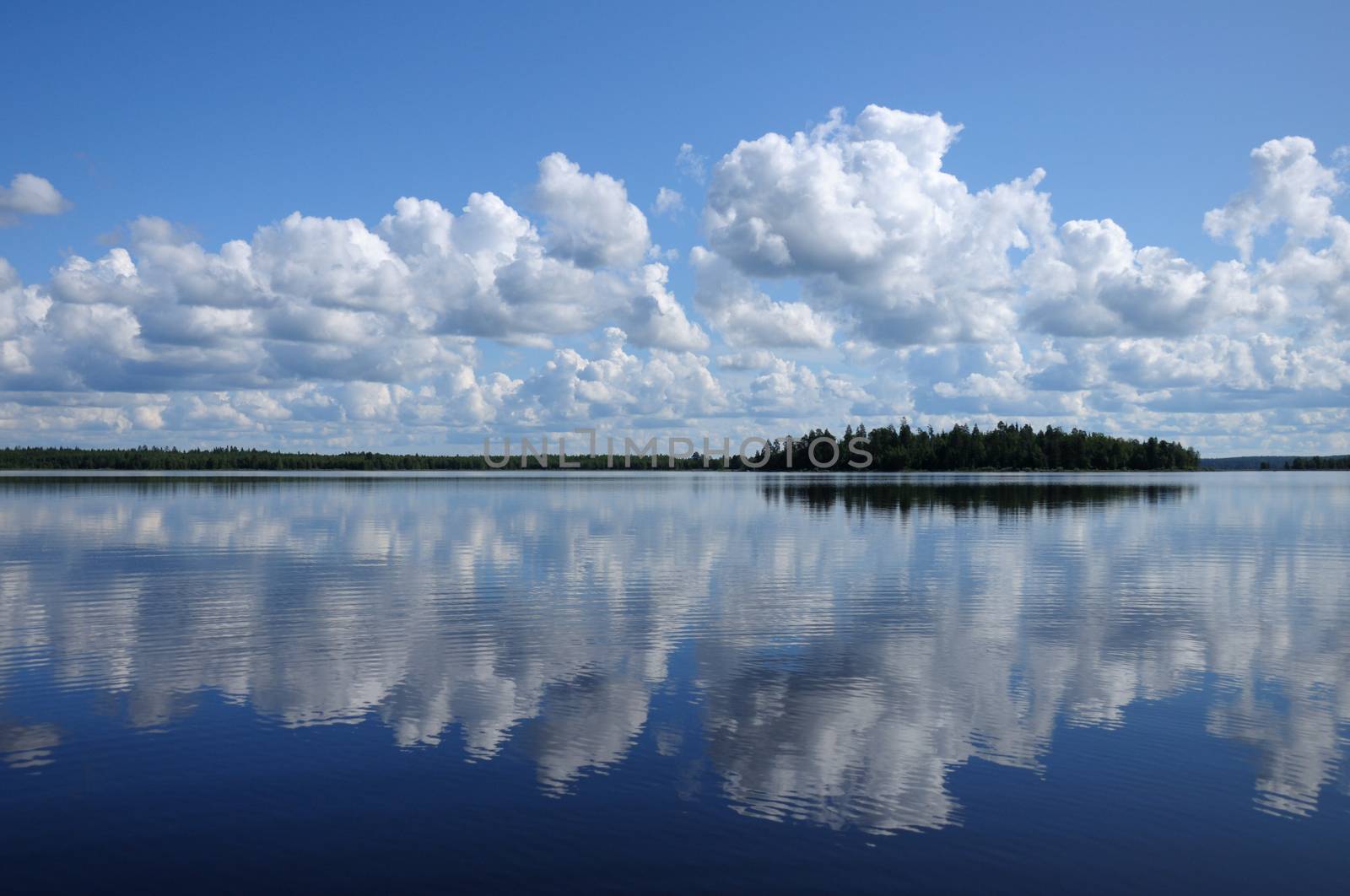 The picture shows typical landscape in the south region of Karelia - blue sky, clouds, big lake looks like a mirror and a lot of distant green islands, trees, stones and rocks