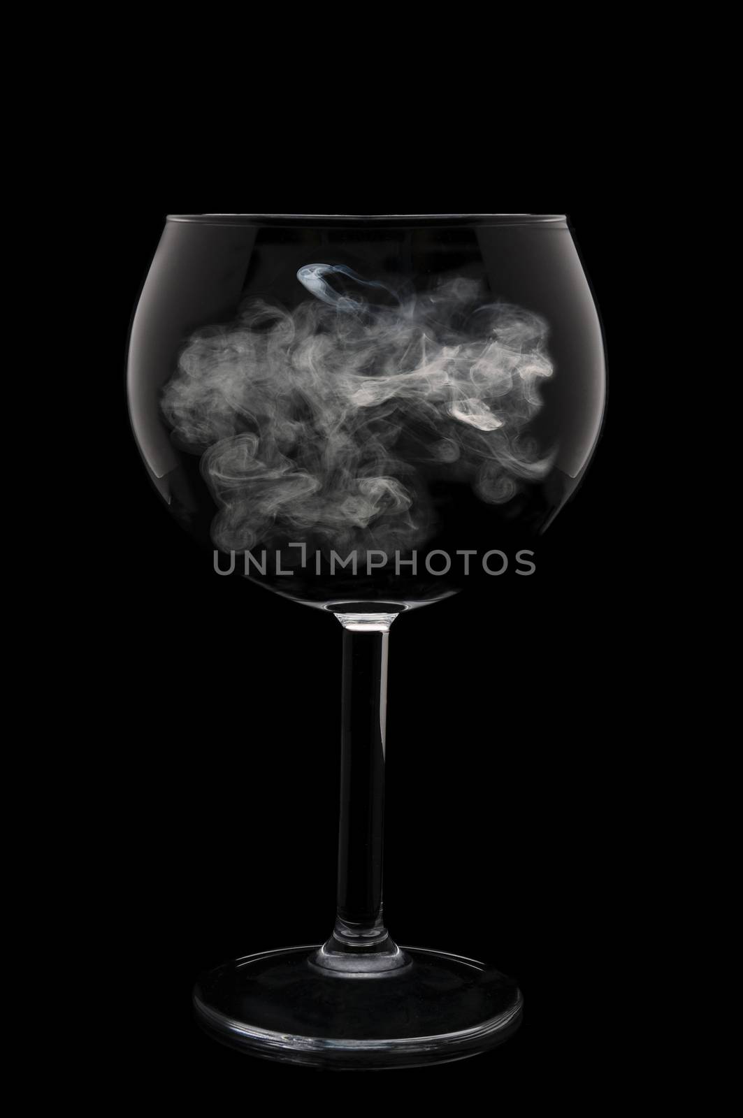 A Wine Glass with a wisp of smoke in the bowl over a black background.