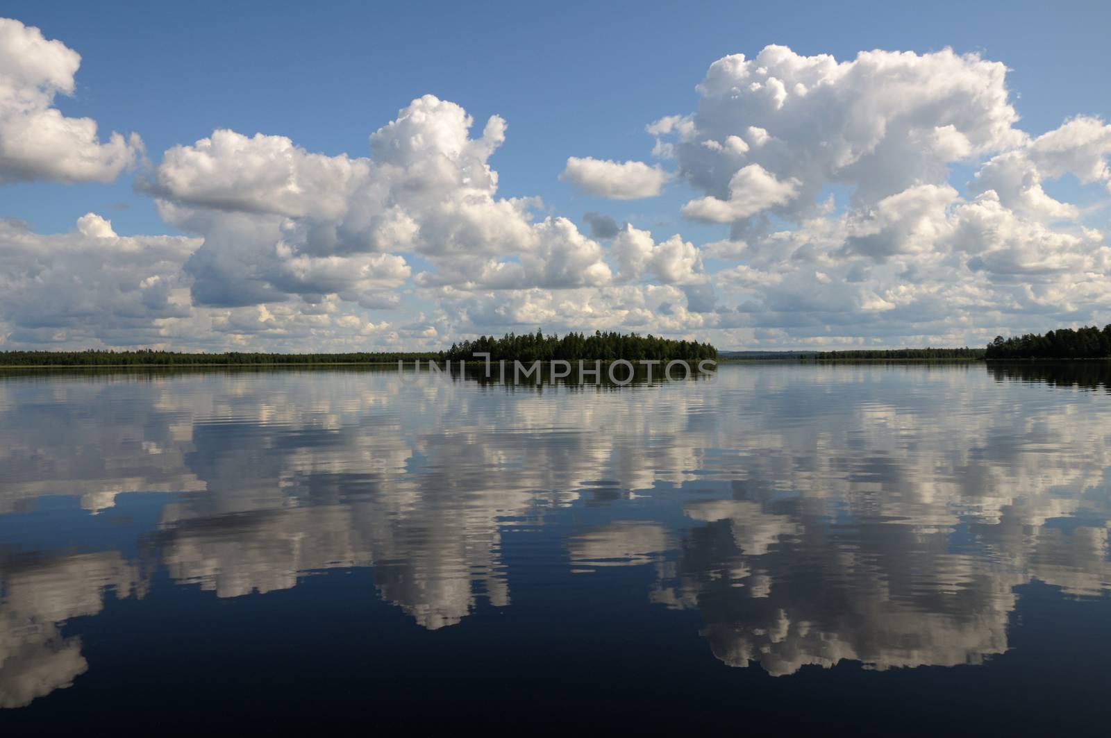 The picture shows typical landscape in the south region of Karelia - blue sky, clouds, big lake looks like a mirror and a lot of distant green islands, trees, stones and rocks