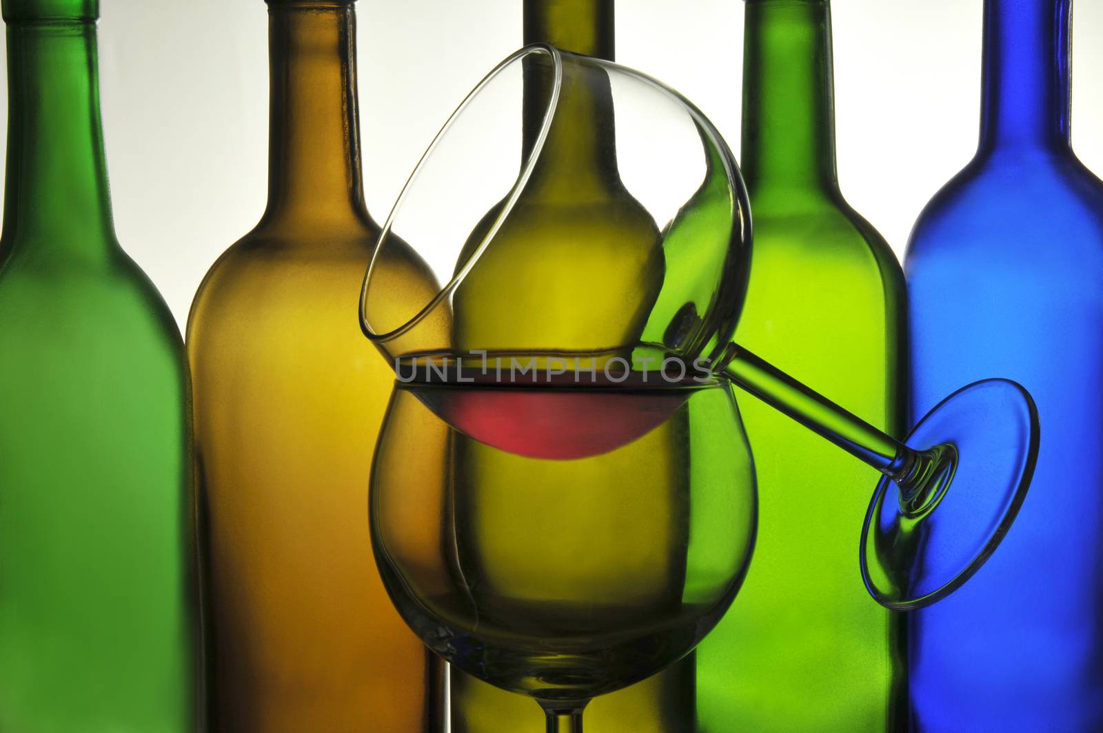 Two Wine Glasses in front of a row of Wine bottles in silhouette with shallow depth of field