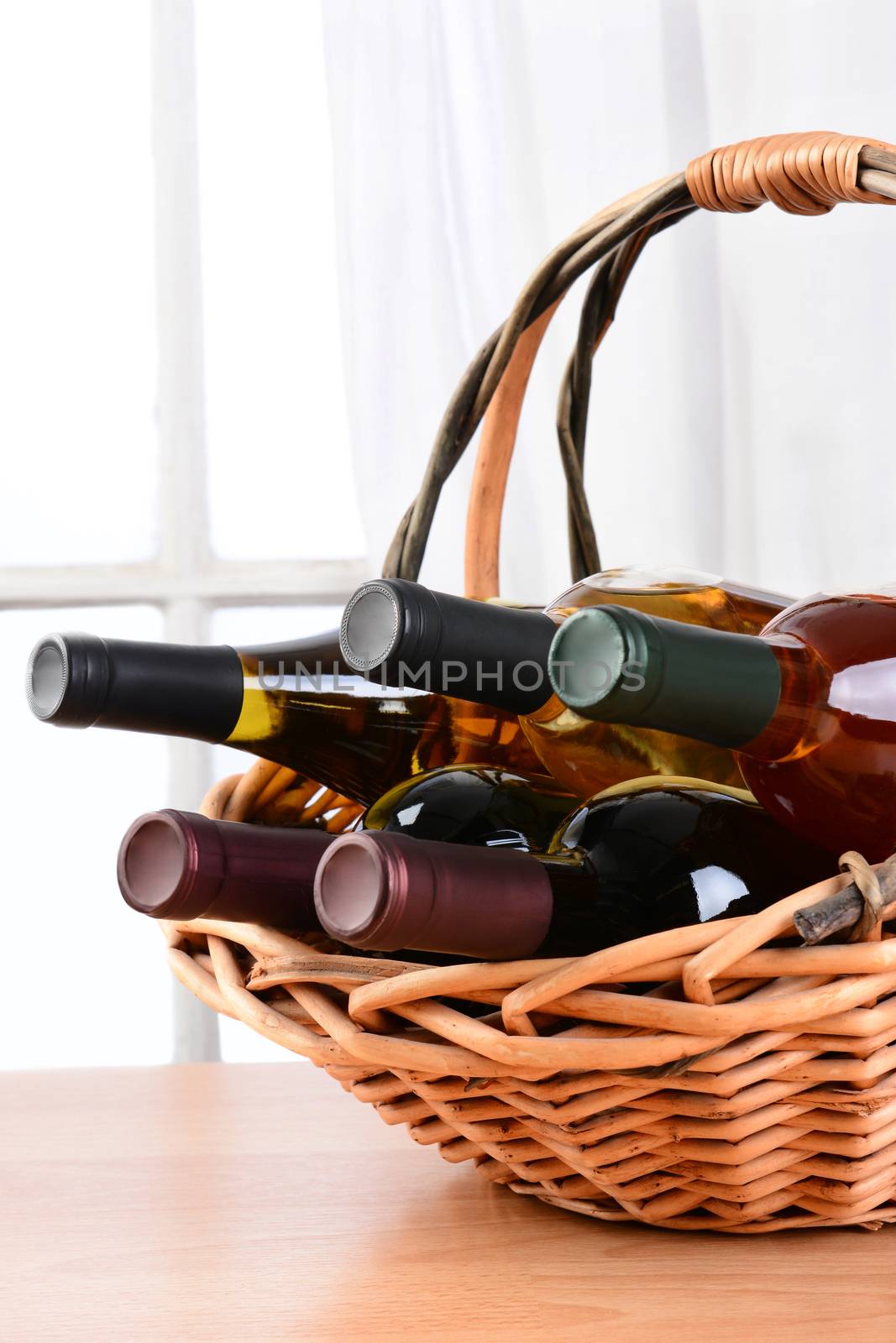 Wine still life with a basket of bottles in front of a window with curtains. Vertical format.