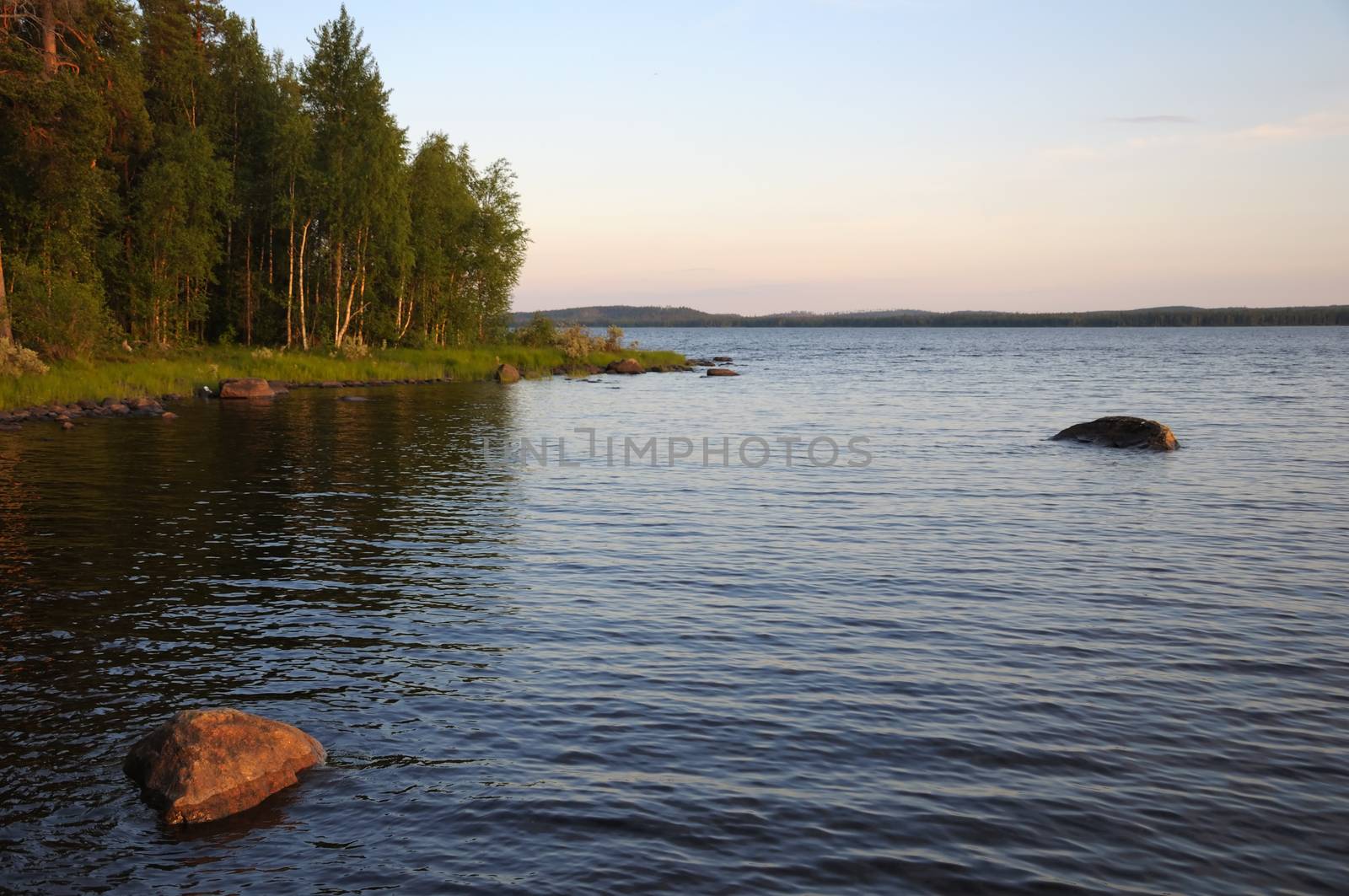 The beautiful picture of Karelian forest at the edge of a lake, and some huge boulder in this lake