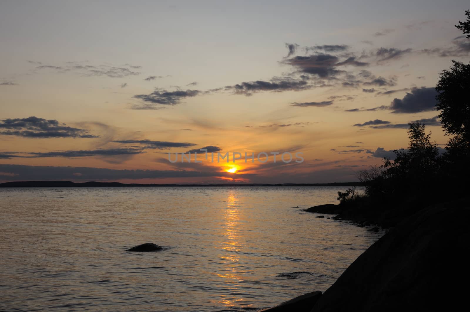 The final stage of a cloudy sunset above the huge lake in Karelia region. The picture is colorful and relaxing.