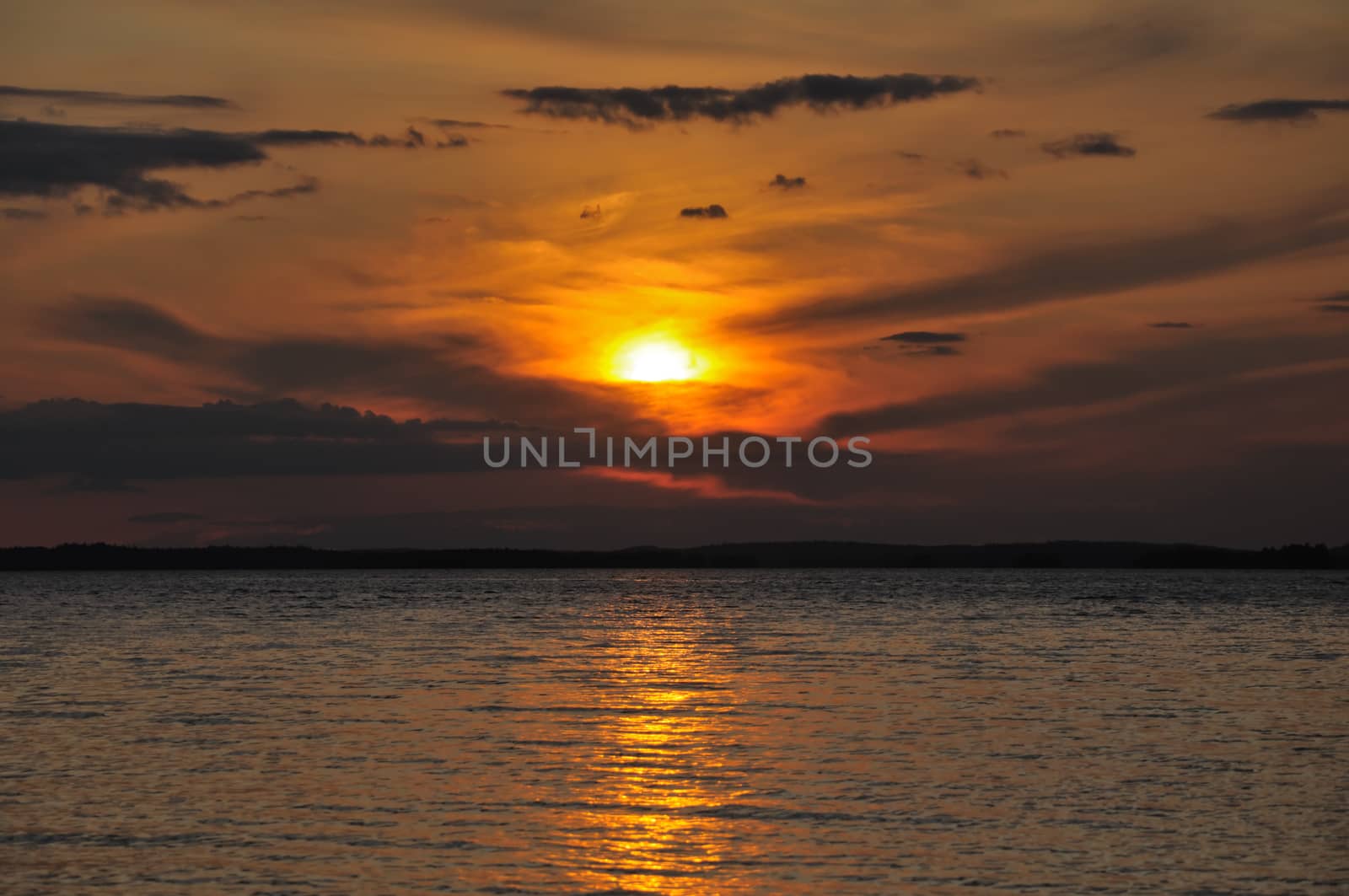 The final stage of a cloudy sunset above the huge lake in Karelia region. The picture is colorful and relaxing.