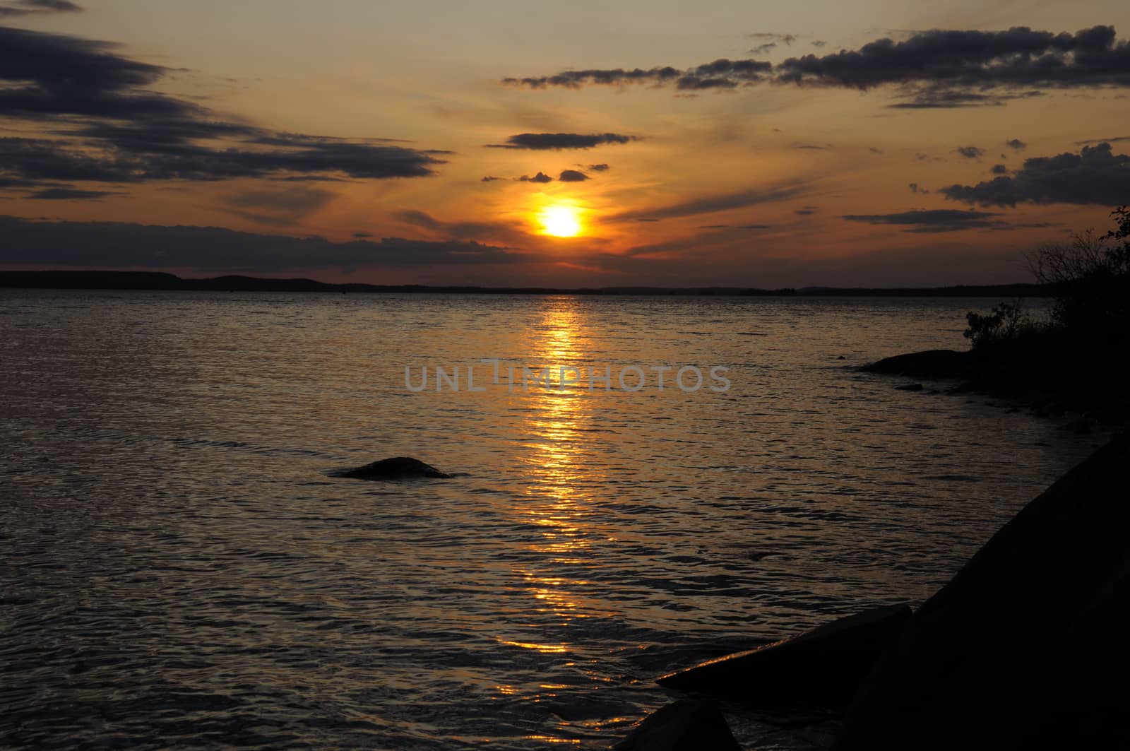 The final stage of a cloudy sunset above the huge lake in Karelia region. The picture is colorful and relaxing.