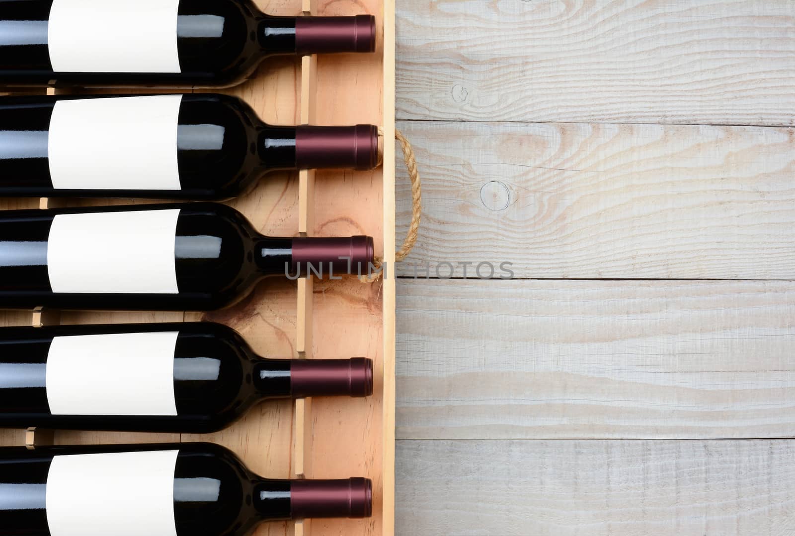 High angle shot of a case of red wine bottles with blank labels  on a rustic white wood table with copy space. Horizontal format.