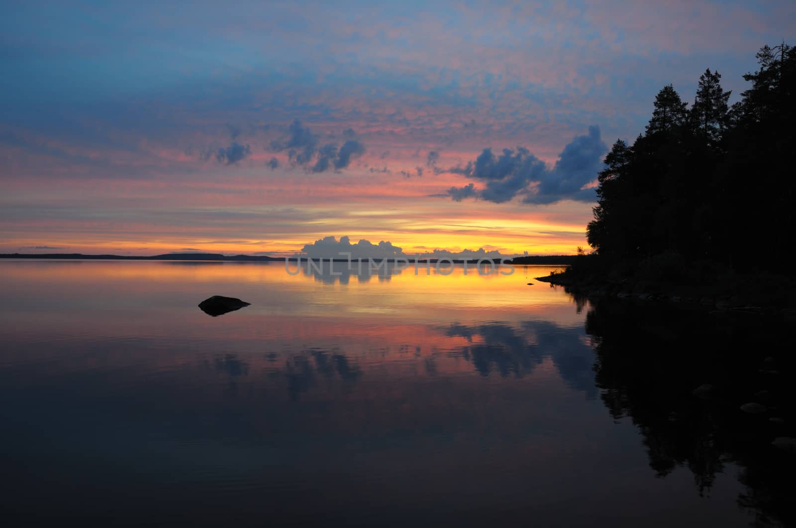 The final stage of a cloudy sunset above the huge lake in Karelia region. The picture is colorful and relaxing.