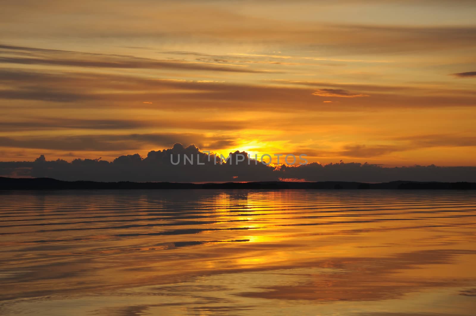 The final stage of a cloudy sunset above the huge lake in Karelia region. The picture is colorful and relaxing.