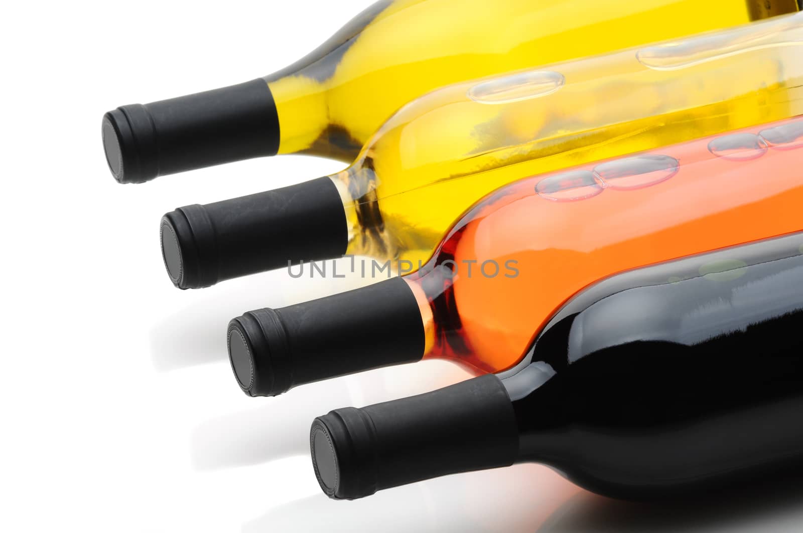 Closeup of four wine bottles laying on their side. Cabernet Sauvignon, White Zinfandel, Pinot Grigio, and Chardonnay bottles are shown, over white with slight reflections in table top.