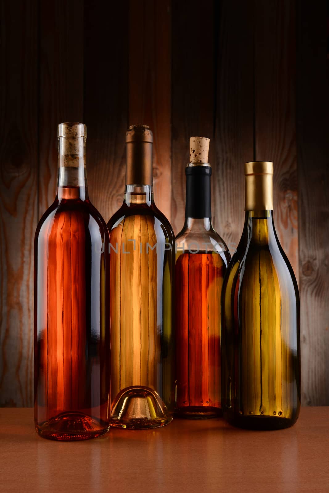 Four wine bottles against a wood background. The bottles have no label and the texture of the background shows through. Vertical format.