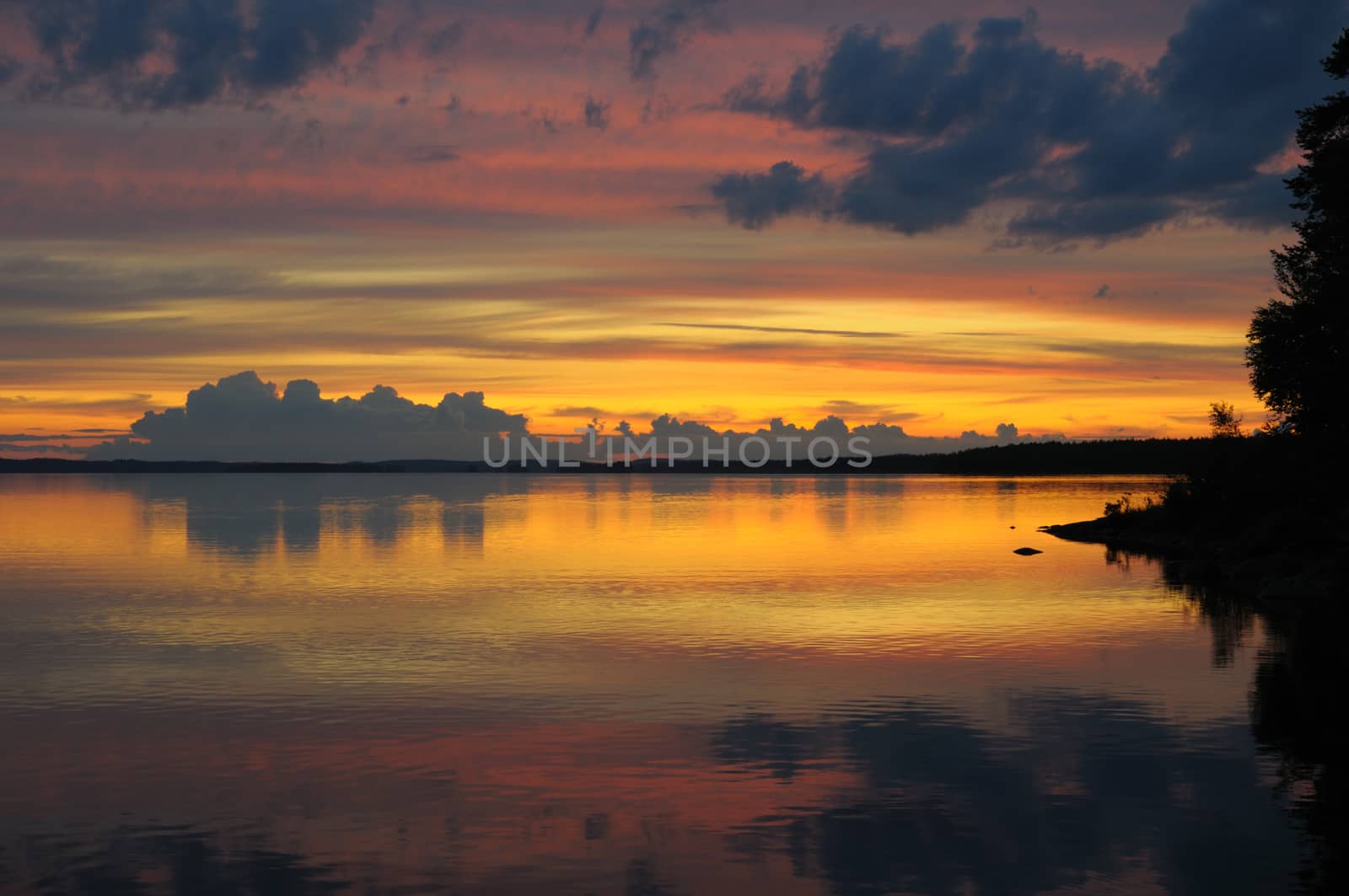 The final stage of a cloudy sunset above the huge lake in Karelia region. The picture is colorful and relaxing.