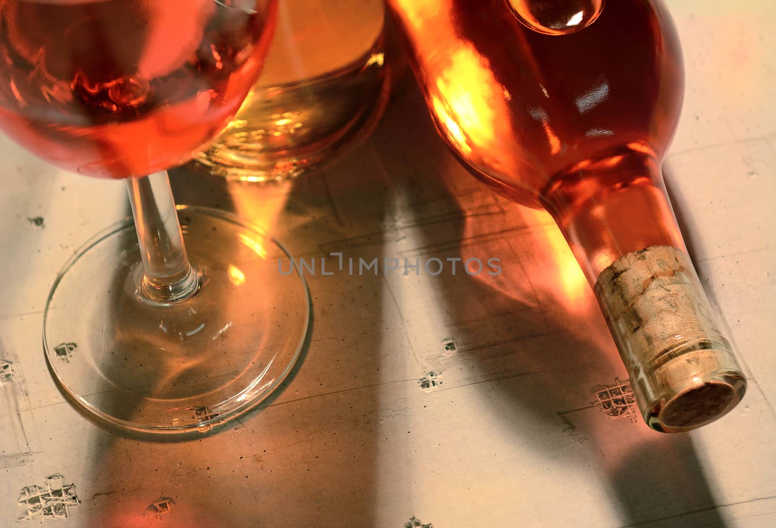 High angle view of a wine bottles and glass with shadows and reflections on a concrete table top.