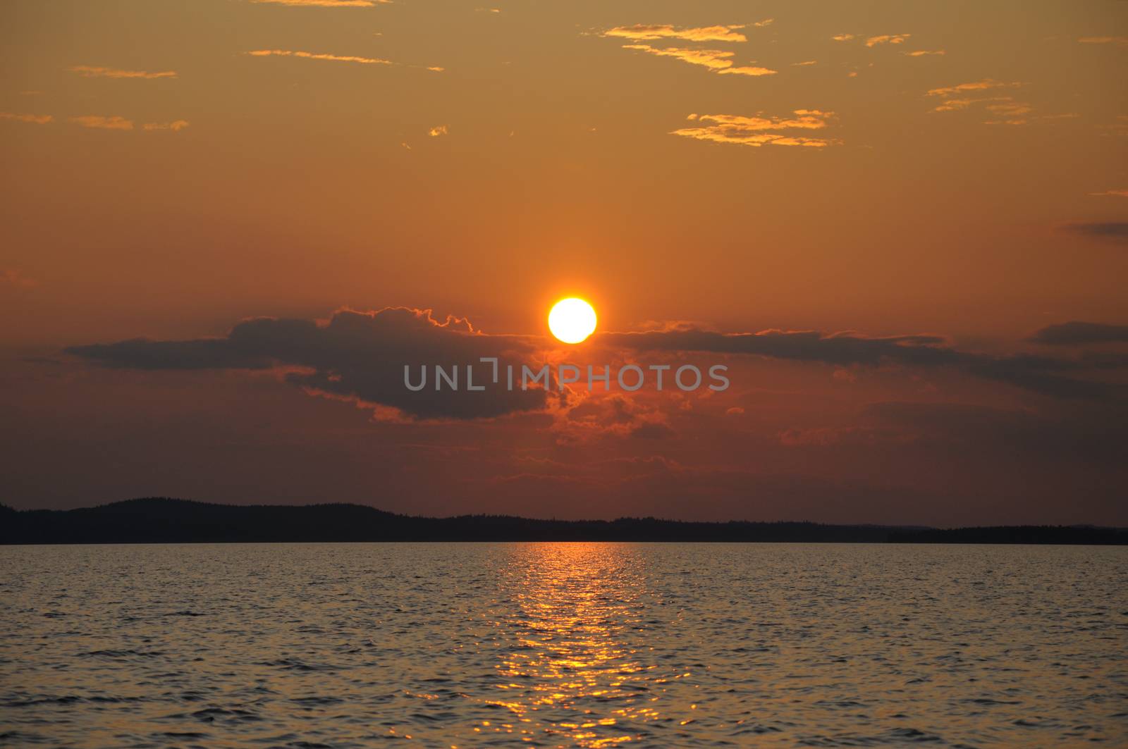 The final stage of a cloudy sunset above the huge lake in Karelia region. The picture is colorful and relaxing.