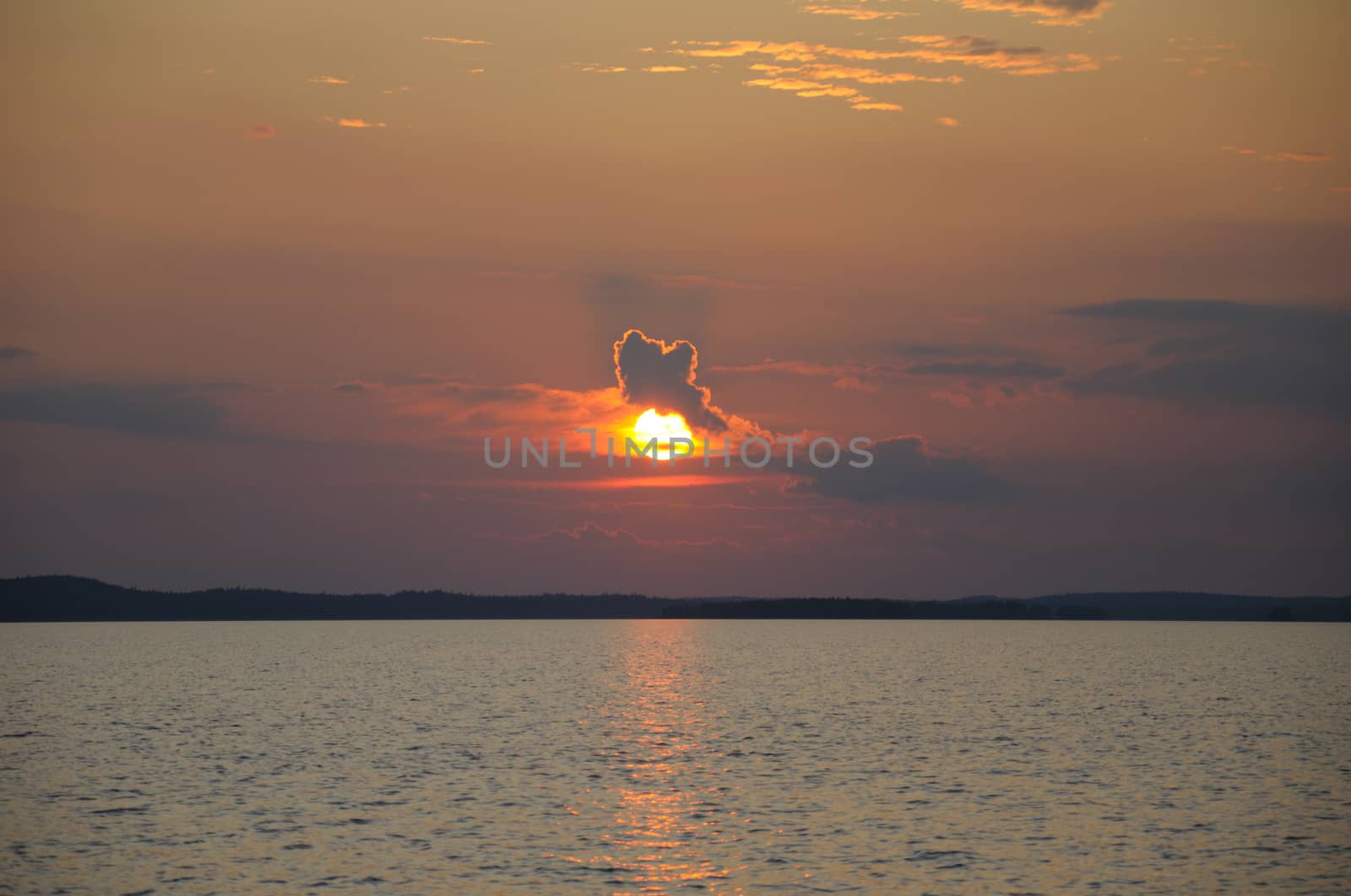 The final stage of a cloudy sunset above the huge lake in Karelia region. The picture is colorful and relaxing.