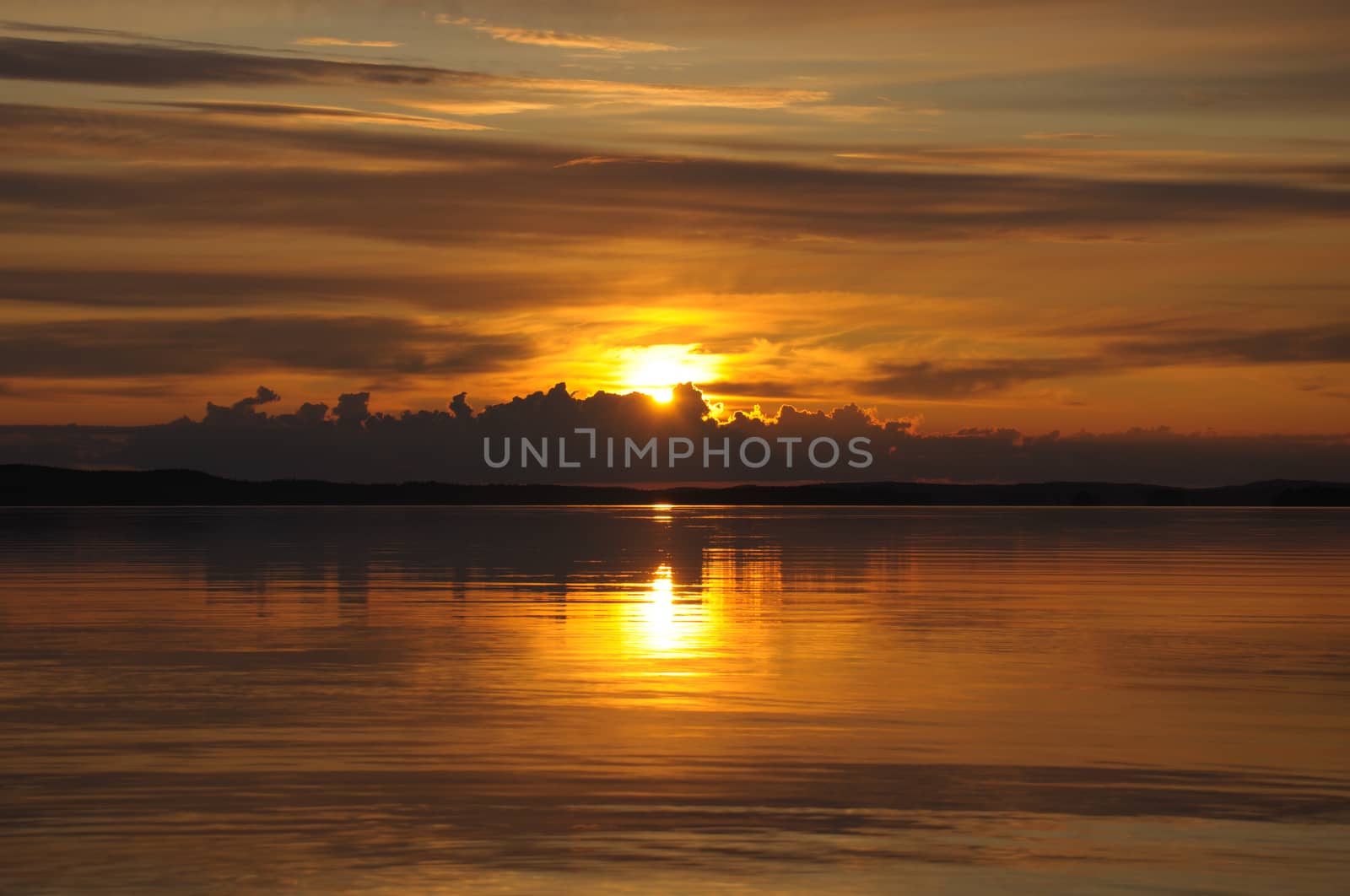 The final stage of a cloudy sunset above the huge lake in Karelia region. The picture is colorful and relaxing.